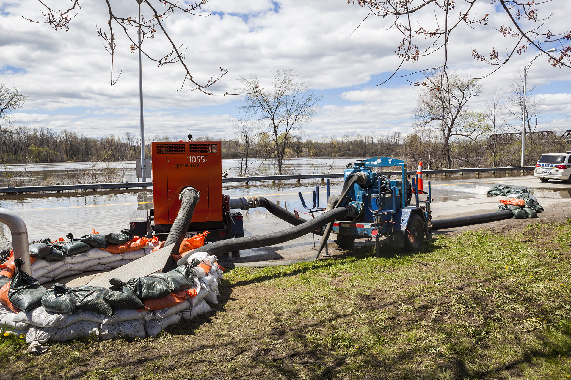 Gatineau, Canada - May 10, 2017: This is the big flood of the city of Gatineau, Quebec, Canada. On this picture, we can see the Gatineau River flooding the Saint-Louis street near the entrance and exit of the Highway 50.  And we can see big water pumps pumping water away from flooded houses and a police car on the road.